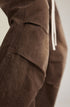Detail view of brown canvas pants showing paneled design over white sneakers