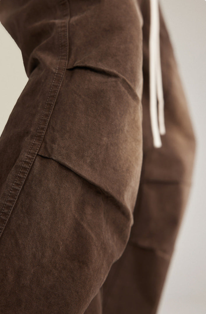 Detail view of brown canvas pants showing paneled design over white sneakers