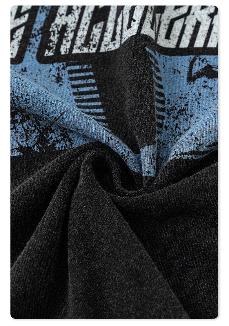 Close-up of blue and white distressed 'B' logo print on black washed fabric showing textile grain and texture
