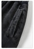 Detail shot of pocket construction on black denim jogger pants with minimalist design against white background