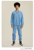 Male model wearing powder blue sweatsuit set with oversized sweatshirt and matching joggers, styled with silver chain necklace and Jordan sneakers