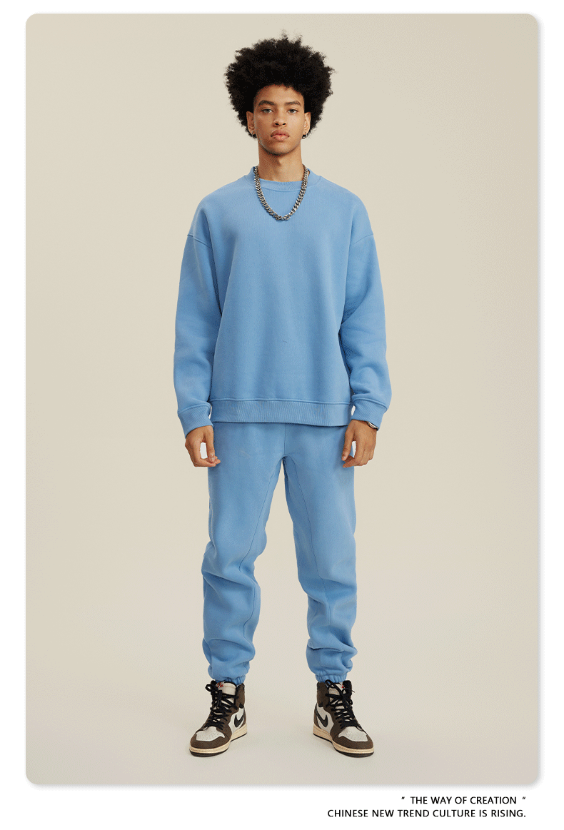 Male model wearing powder blue sweatsuit set with oversized sweatshirt and matching joggers, styled with silver chain necklace and Jordan sneakers