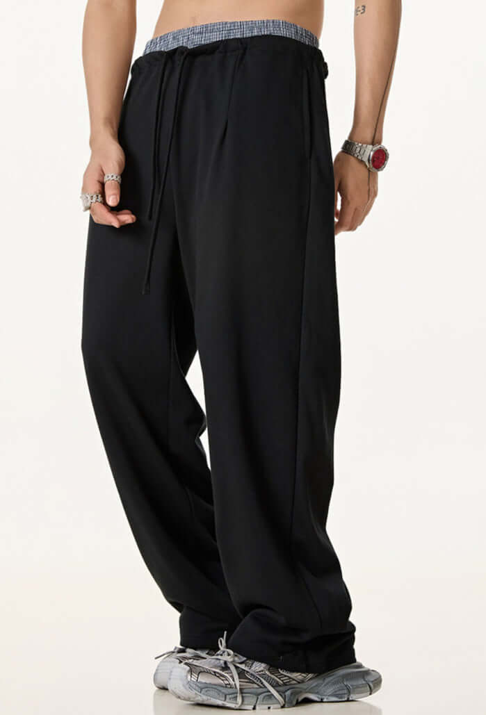 Side view of black sweatpants highlighting the relaxed fit, elastic waistband, and drawstring closure.