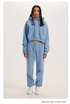 Sky Blue Sweatshirt and Joggers Set – Model in a pastel blue hoodie and joggers, styled with white sneakers