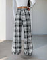 Back view of black and white plaid wide-leg pants featuring an elastic waistband, styled with a white long-sleeve top.
