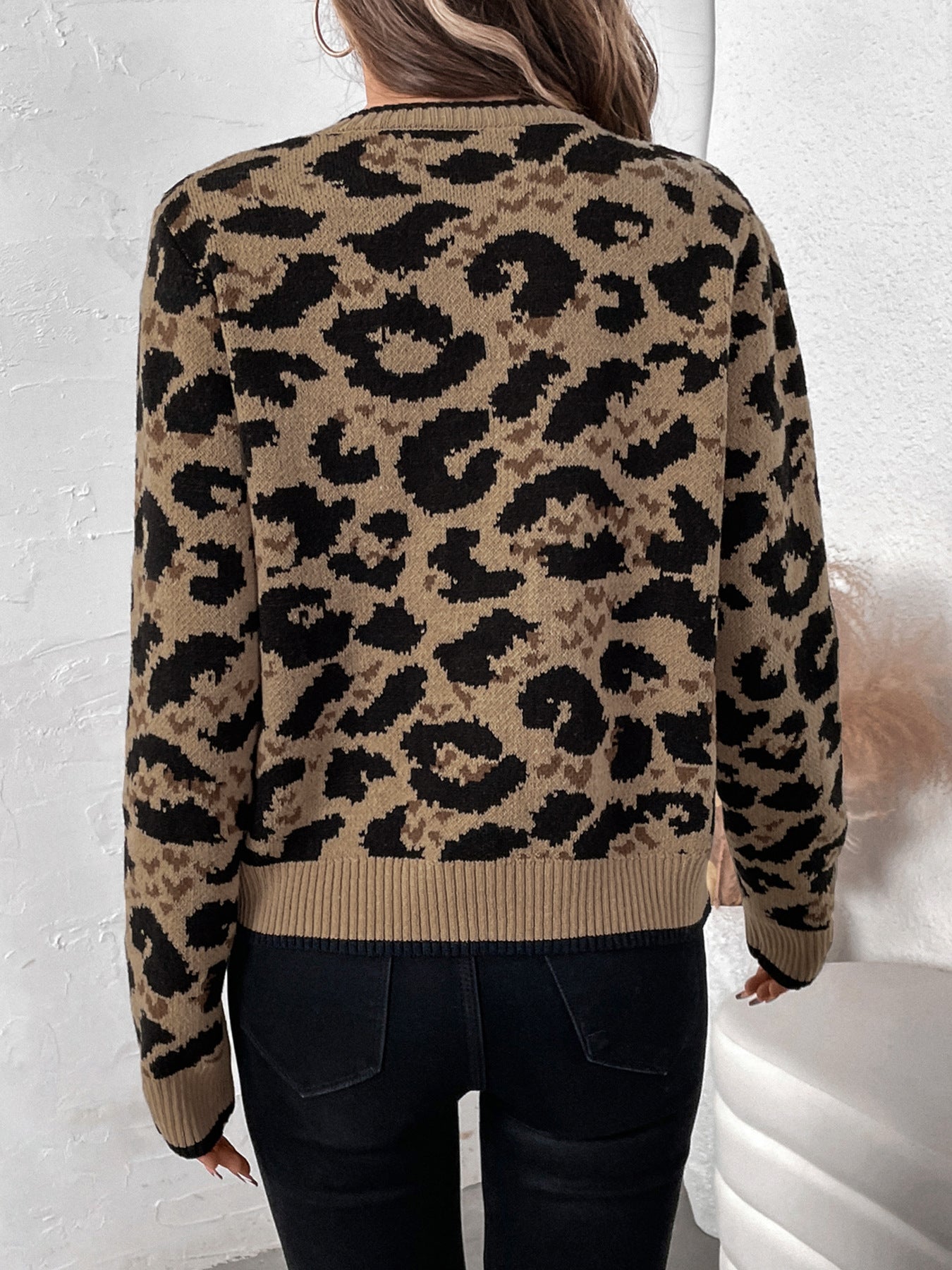 Back view of tan and black leopard print cardigan showing full pattern detail against white wall