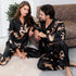 Matching black couple's silk pajamas with golden dragon print, featuring long-sleeve top and pants for coordinated loungewear