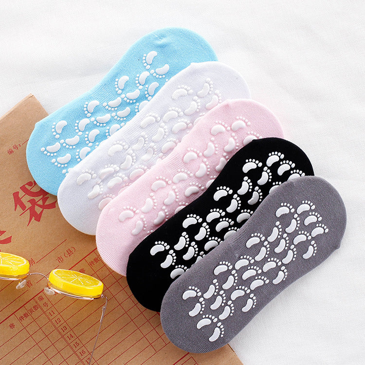 Five colorful non-slip socks with footprint grippers in blue, white, pink, black, and gray arranged in fan layout against white background