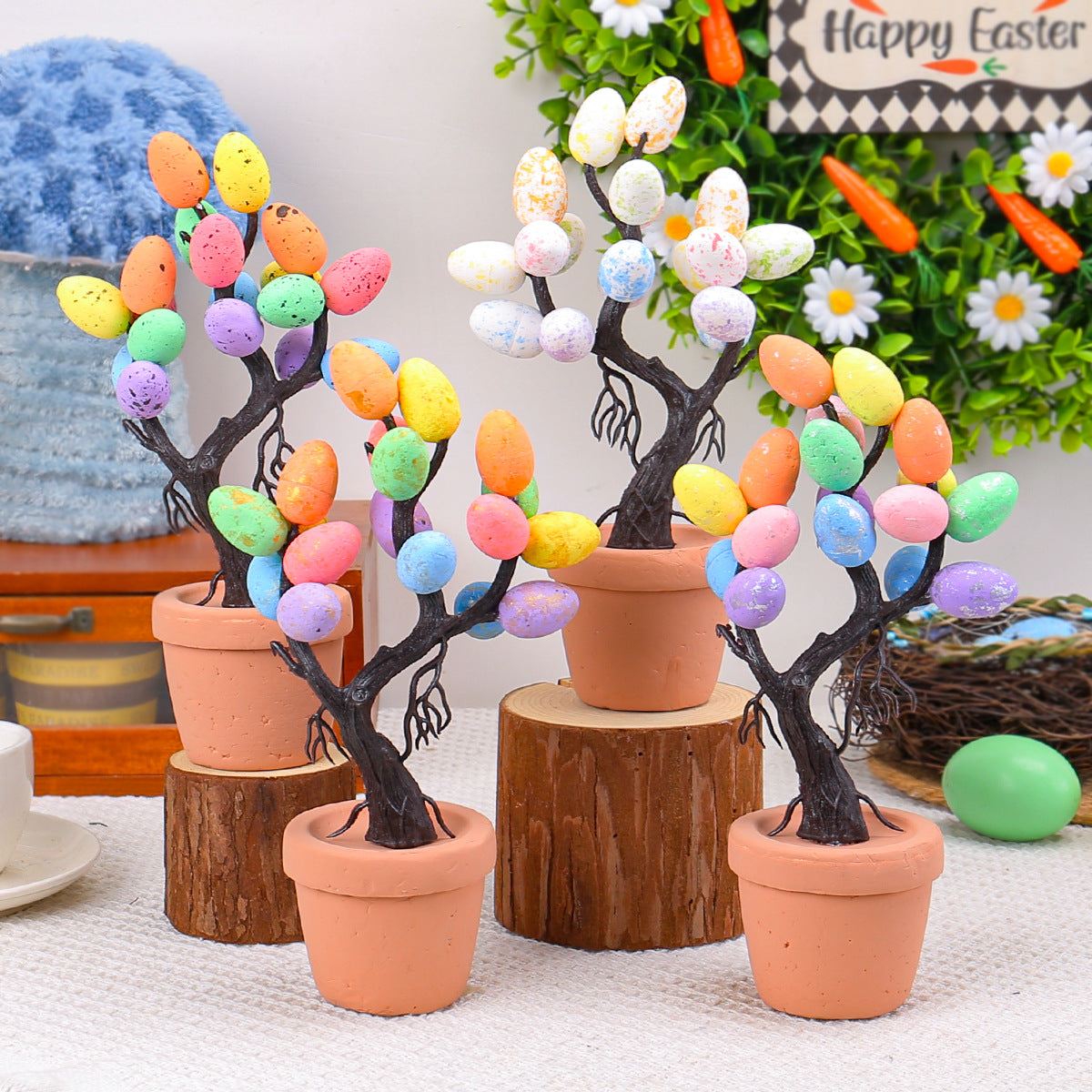 A set of four decorative Easter egg trees with vibrant pastel-colored eggs on dark twisted branches, placed in terracotta pots for a festive display.