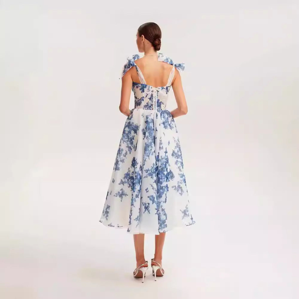 Back view of white and blue floral organza dress, showcasing detailed bow straps and fitted silhouette