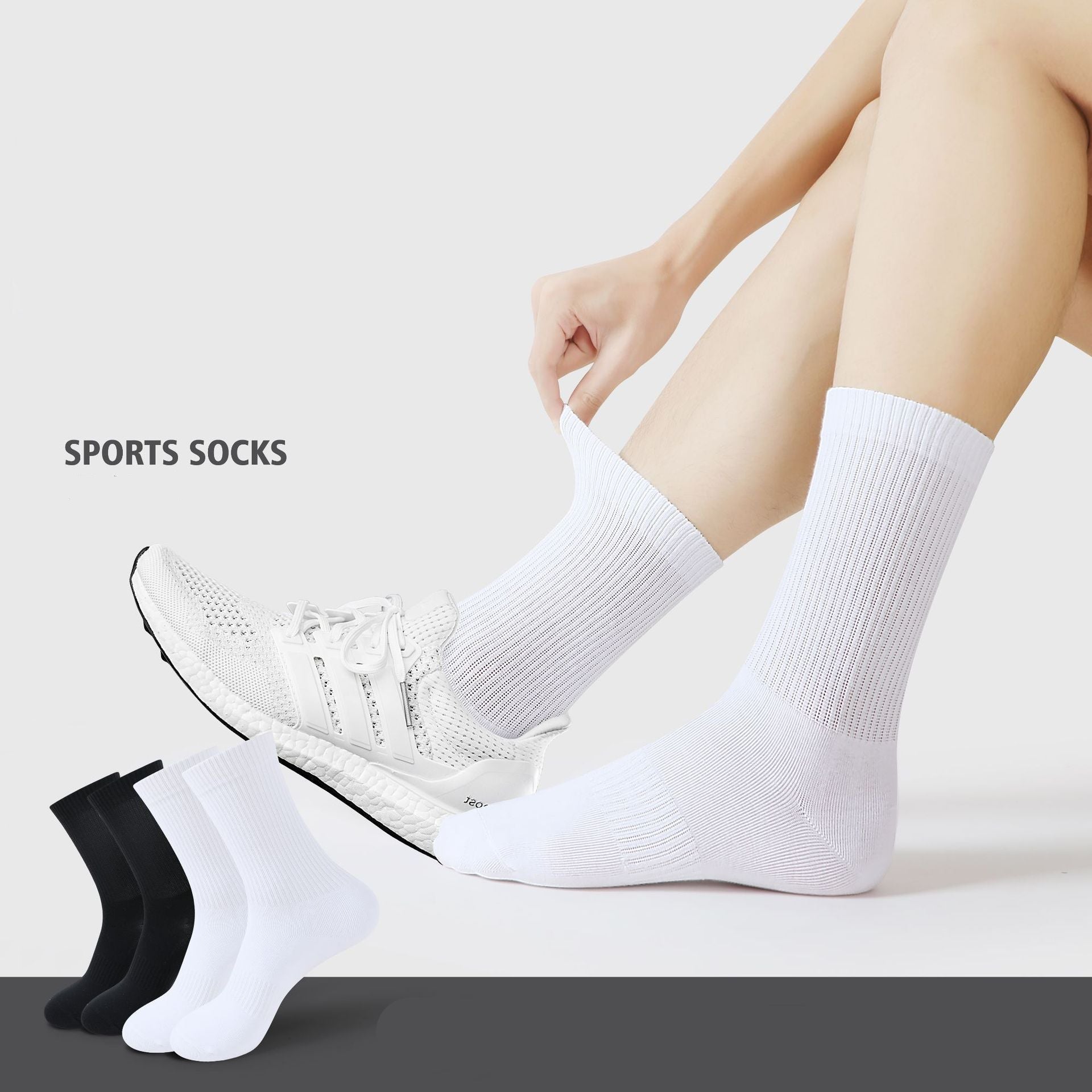 A model wearing white ribbed sports socks with white athletic shoes. Black and white sock pairs displayed below against gray background