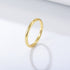 A gold thin stackable band ring with 925 stamp displayed on white surface casting subtle shadow