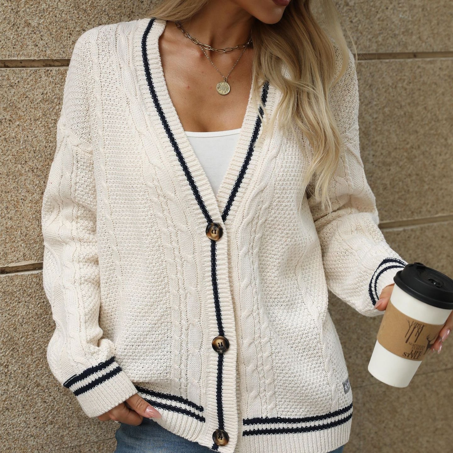 White cable knit cardigan with navy trim, paired with white tank and black wide-brim hat for chic casual look