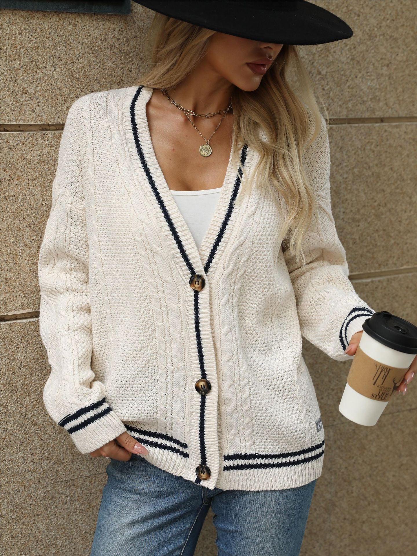 White cable knit cardigan with navy trim, paired with white tank and black wide-brim hat for chic casual look
