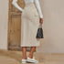 Side view of cream cargo midi skirt with pocket detail, styled with white platform sneakers and chain bag