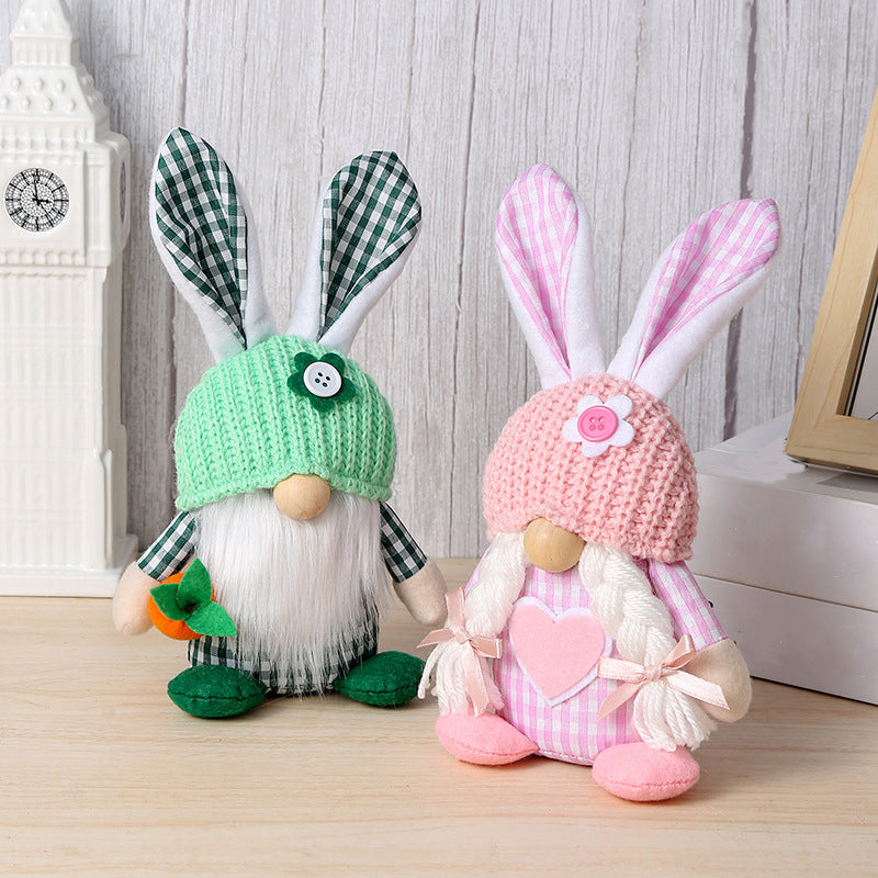 Green and pink bunny gnome plush toys with gingham ears and knit hats, displayed on a wooden surface.