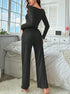 Back view of black ribbed loungewear jumpsuit with fitted waist and wide-leg pants, model standing by window with white decor
