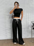Full outfit with black crop top and wide-leg pants, leopard bag and headphones