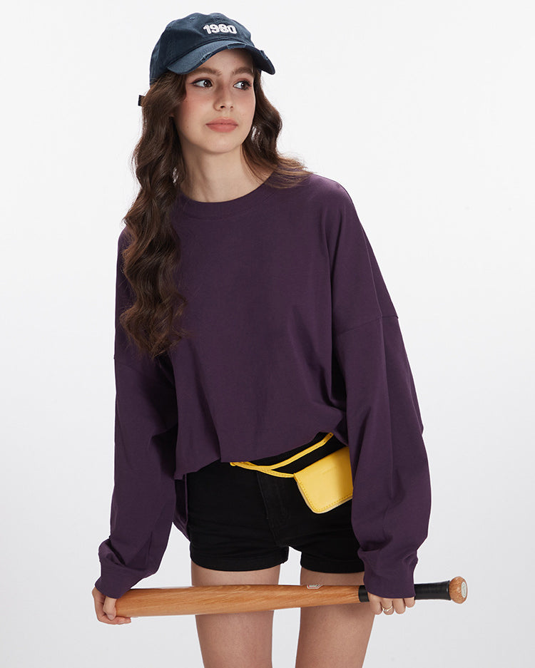 Purple oversized sweatshirt with crew neck and dropped shoulders, paired with black shorts and yellow belt bag