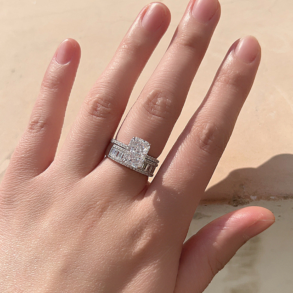 A woman wearing silver engagement ring with matching wedding band featuring baguette diamonds and cushion-cut center stone in sunlight