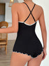 A black ribbed romper with crisscross adjustable straps and white ruffle trim, showcasing the open-back design.