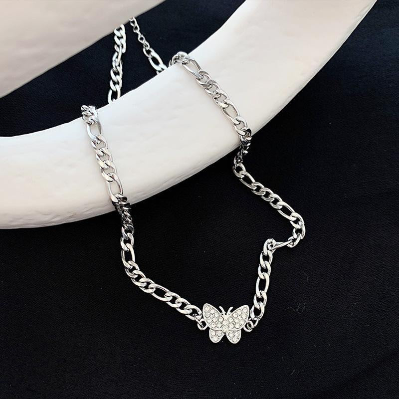 Silver Figaro chain necklace with crystal butterfly pendant displayed on black and white background