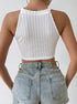 Back view of white ribbed knit halter crop top paired with distressed denim shorts.