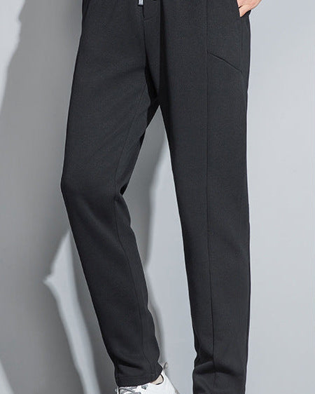 Black slim-fit pants with white drawstring and white-tipped sneakers