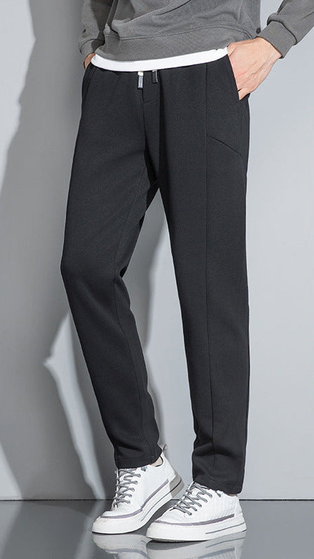 Black slim-fit pants with white drawstring and white-tipped sneakers