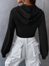 Back view of black textured crop hoodie showing fitted silhouette with balloon sleeves and white cargo pants