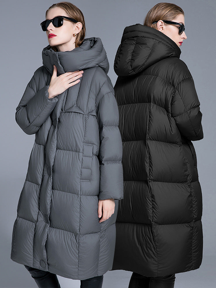 Two women modeling quilted puffer coats, one in gray and one in black, standing back-to-back wearing sunglasses with slicked-back hair against gray background