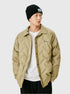 A man wearing a black ribbed beanie and tan quilted shirt jacket with embroidered logo, posing against white background
