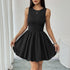 A woman holding out the hem of her black sleeveless dress, showing the flared bubble skirt design, standing in a bright indoor setting.