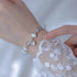 White crystal bracelet styled with lace sleeve detail, featuring silver cage charm