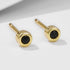 Close-up of gold-plated round stud earrings with black nano zirconia stones on white surface
