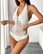 Woman wearing a white lace halter bodysuit with sheer floral mesh and cutout sides.