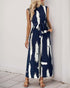 Woman wearing a navy sleeveless jumpsuit with white brushstroke print, a belted waist, and wide-leg pants, styled with neutral sandals.
