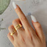 Hand wearing gold butterfly rings: wide band with cutout design and delicate band with raised butterfly