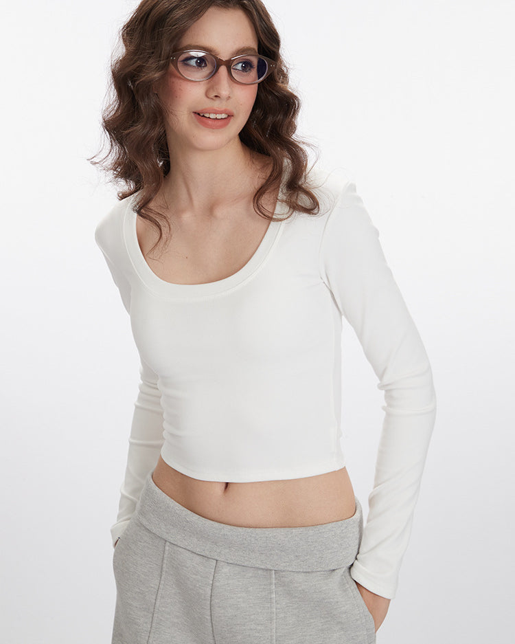 White long-sleeve crop top with scoop neckline and fitted silhouette, paired with light gray wide-leg pants with pockets
