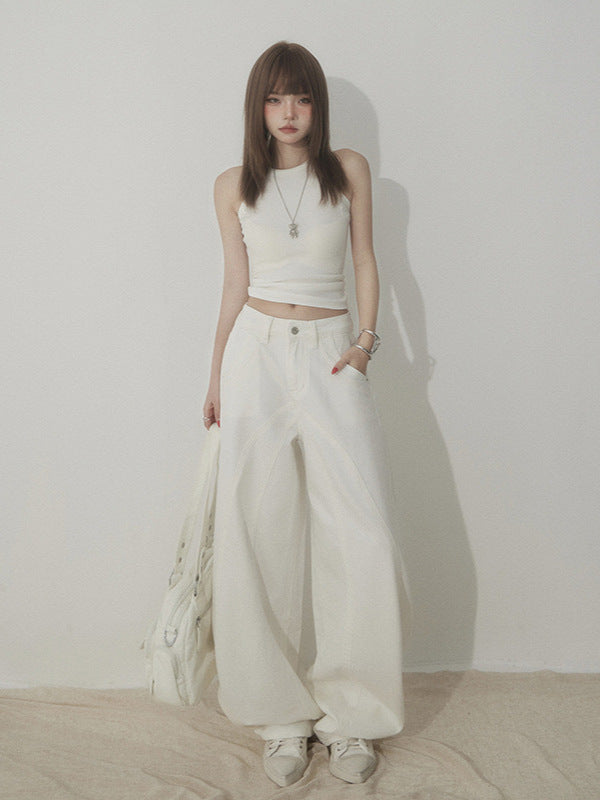 Front view of white wide-leg jeans with curved seam detail, styled with white crop top.