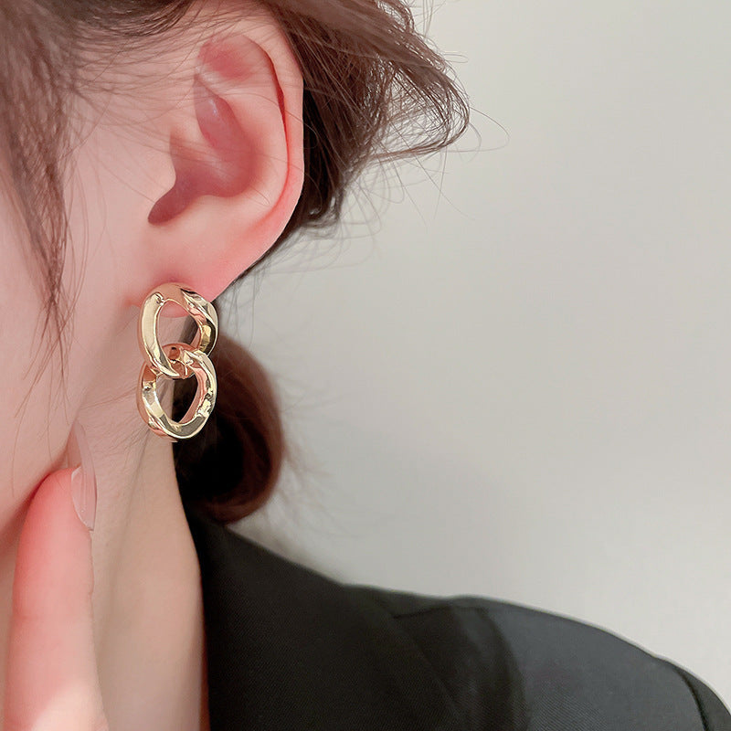 Gold chain link dangle earrings on ear