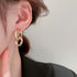 Gold chain link dangle earrings on ear
