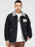 Model wearing black denim jacket with gray sherpa collar, white t-shirt and distressed brown pants. Features OP patch logo