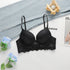 A black push-up bra with delicate lace trim displayed on white surface beside light denim fabric and blue roses. Wooden candle holder visible
