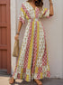 Woman in a bohemian jumpsuit with patchwork prints in red, yellow, and white, carrying a woven handbag and wearing sandals.