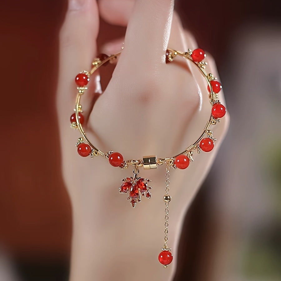 Elegant red agate bracelet with maple leaf charm and gold-tone details