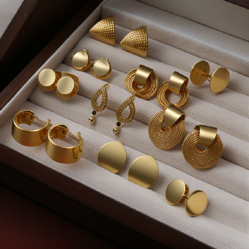 Gold Earring Set in Jewelry Box – A collection of gold earrings with various modern designs displayed in a velvet-lined jewelry box