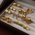 Gold Earring Set in Jewelry Box – A collection of gold earrings with various modern designs displayed in a velvet-lined jewelry box