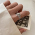 Silver skeleton hand ring on a finger, holding a vintage black-and-white photo, styled with a beige sleeve