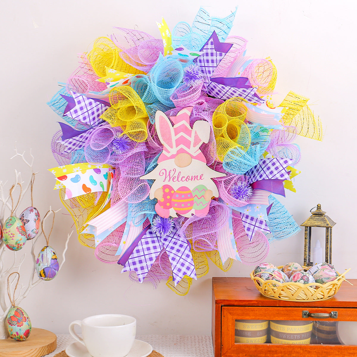 Colorful Easter wreath with ribbons and bunny gnome sign, decorated with pastel mesh and plaid bows.